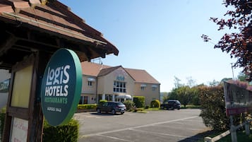 A hotel with a sign for 'Loris Hotels Restaurants' and a parking lot with cars.