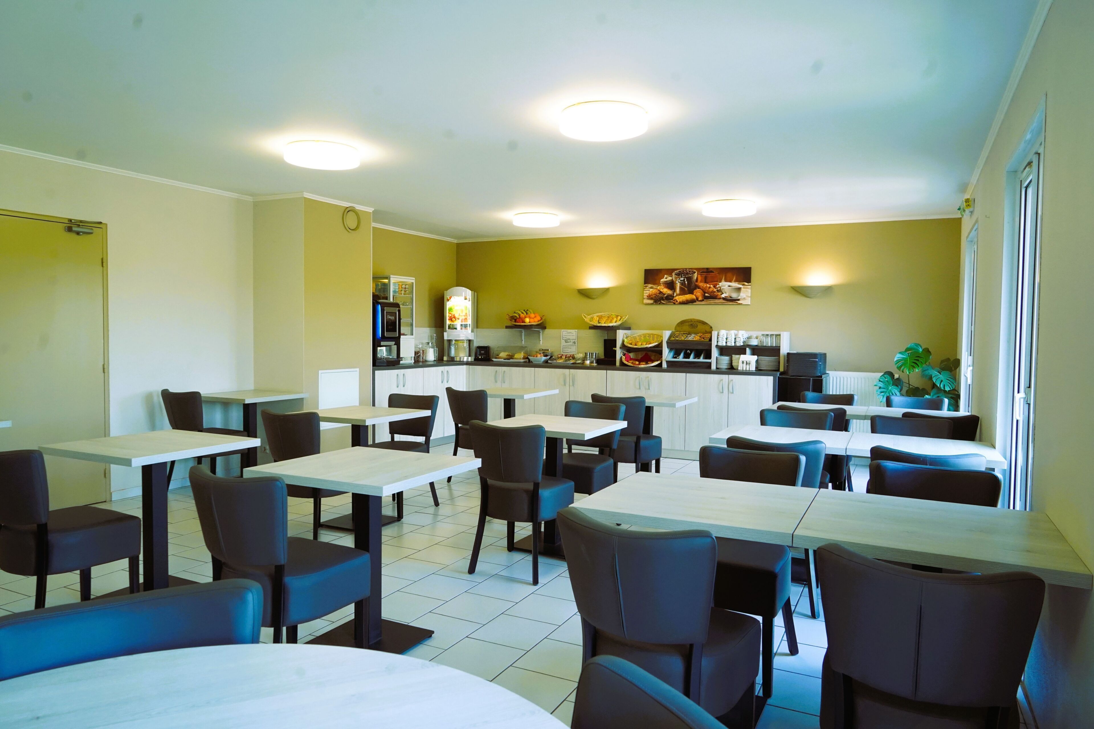 A restaurant with tables and chairs, a counter with a coffee machine, and a wall with a fruit display.