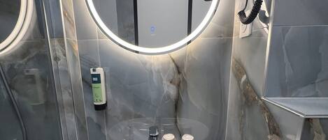 Un baño moderno con un espejo redondo, un lavamanos y un teléfono portátil.