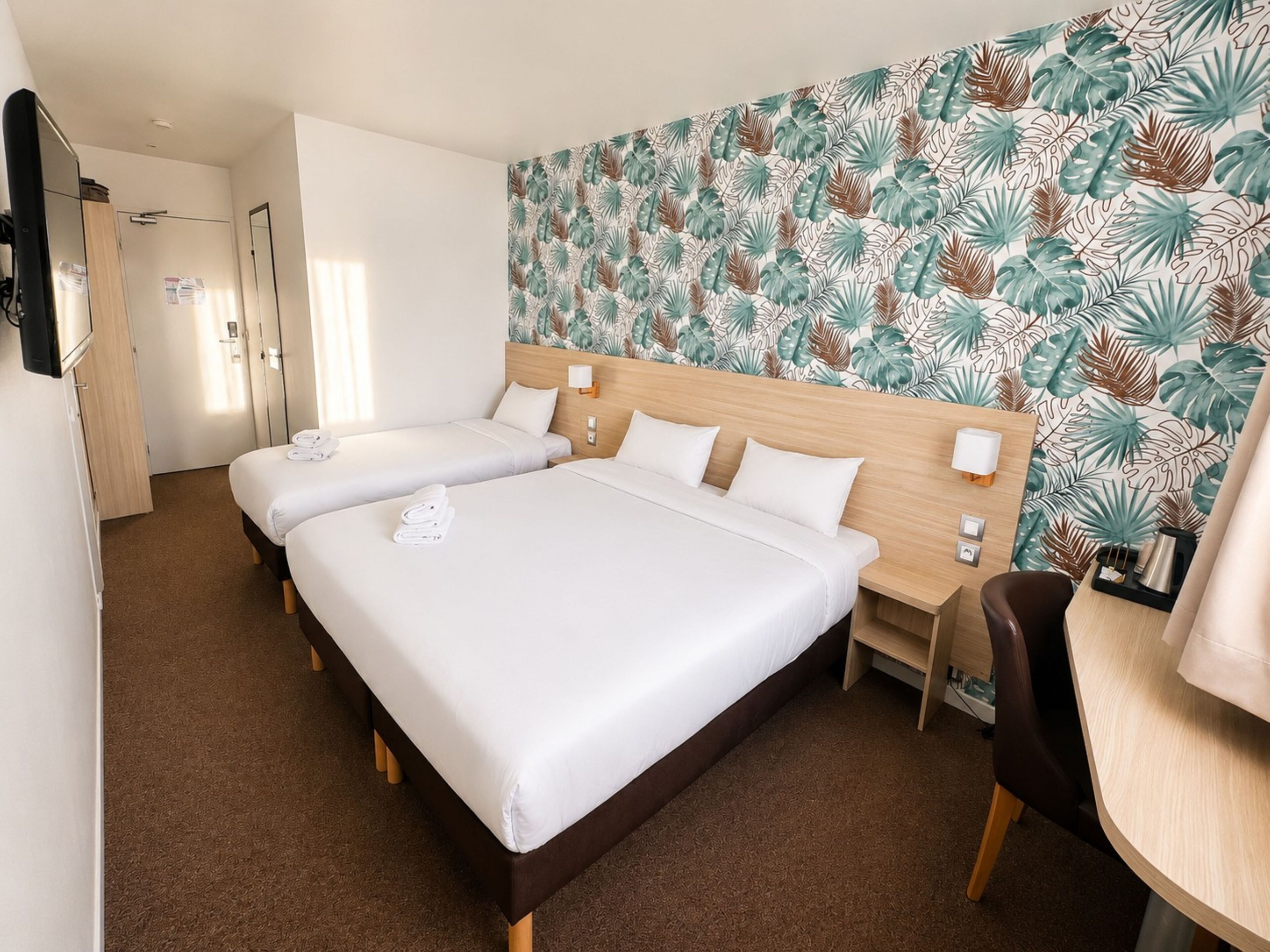 Une chambre d’hôtel avec deux lits, un bureau, une chaise et une salle de bain.