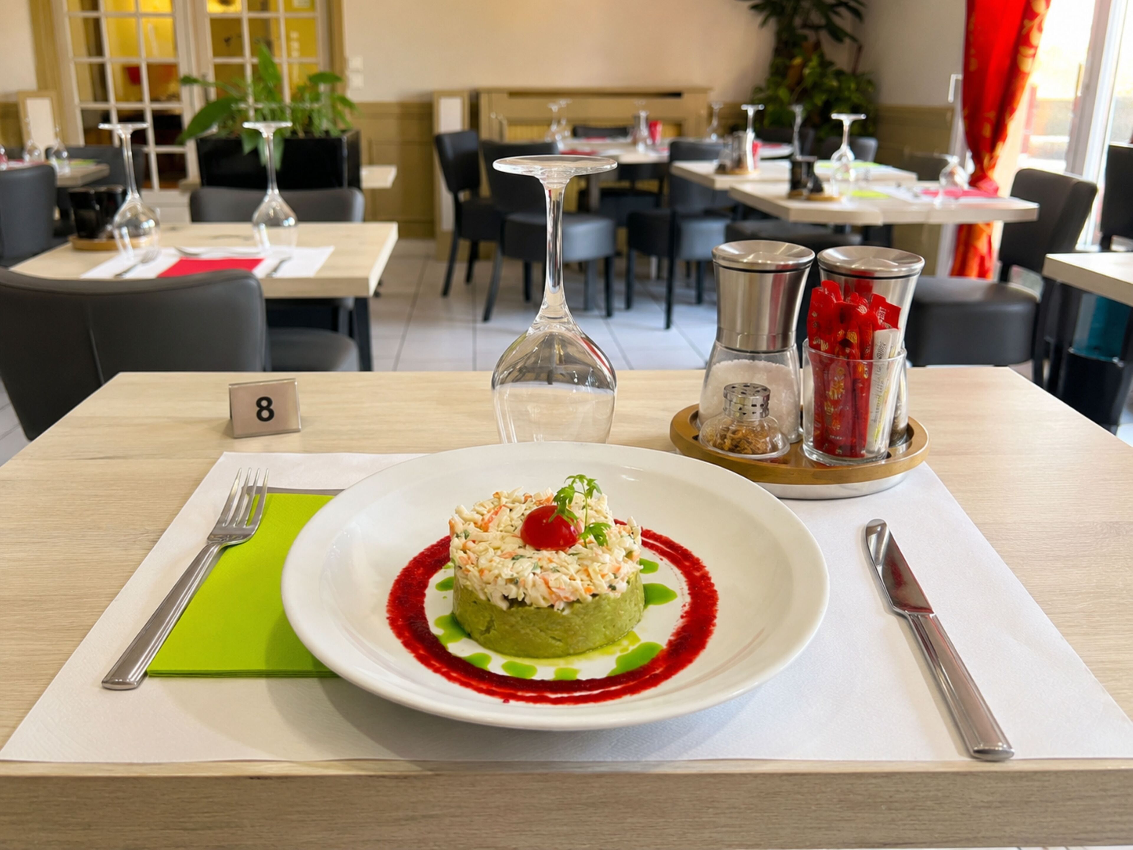Une table à manger avec une assiette de nourriture, une fourchette, un couteau et une serviette.