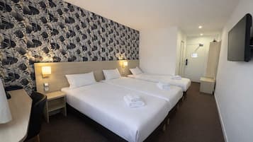 Une chambre d’hôtel avec un grand lit, deux tables de chevet, un bureau, une chaise et un téléviseur fixé au mur.