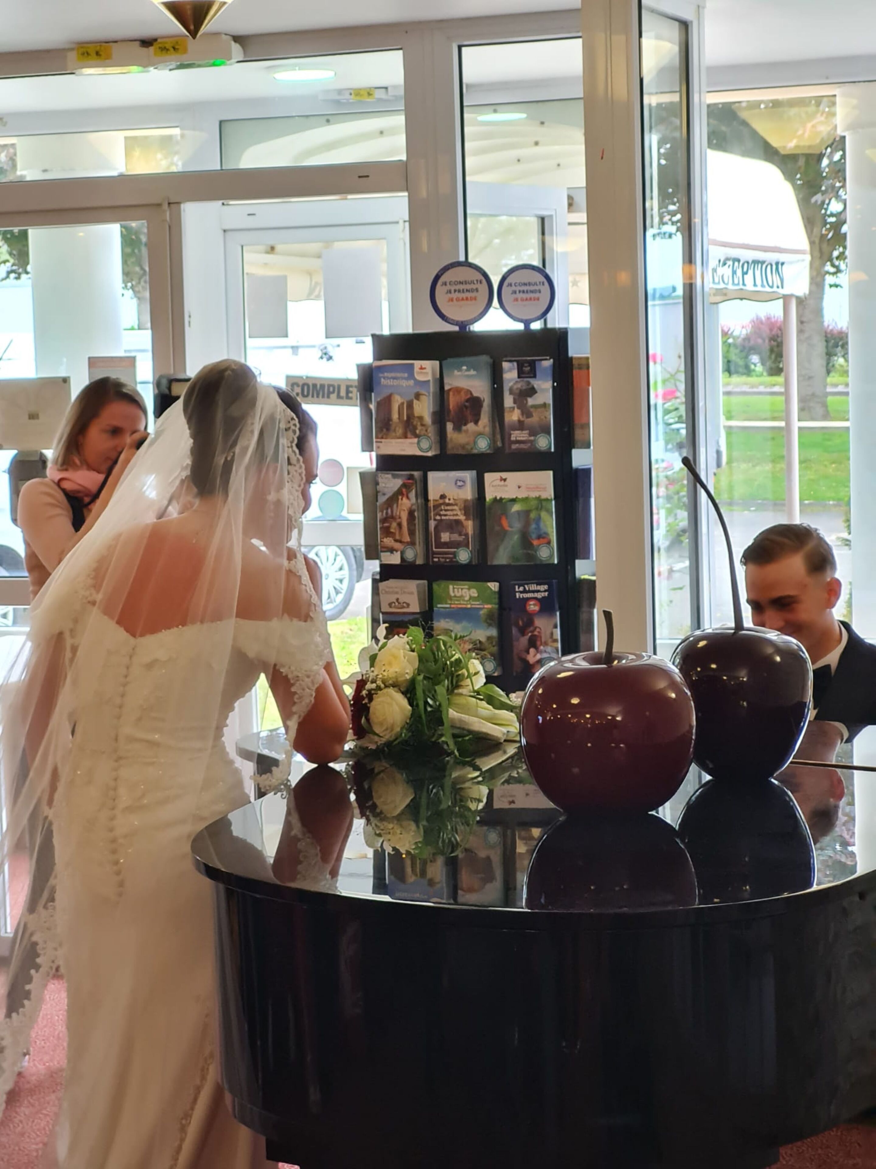 A reception area with a glass window, a black counter, and a display of books.
