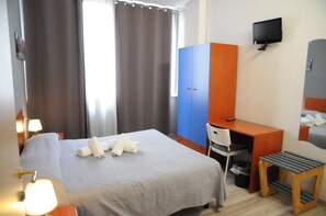 A hotel room with a bed, a desk, a chair, a TV, and a window with curtains. - Scacco Matto (Milan)