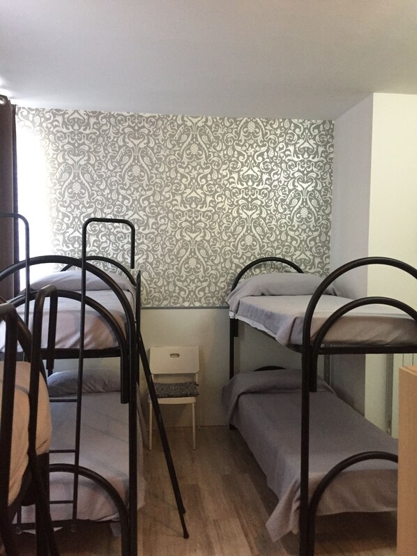 Un dormitorio con literas, una mesita de noche pequeña y papel tapiz estampado.