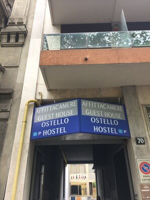 A hostel entrance with signs for 'Affittacamere Guest House Ostello'. - Scacco Matto (Milan)