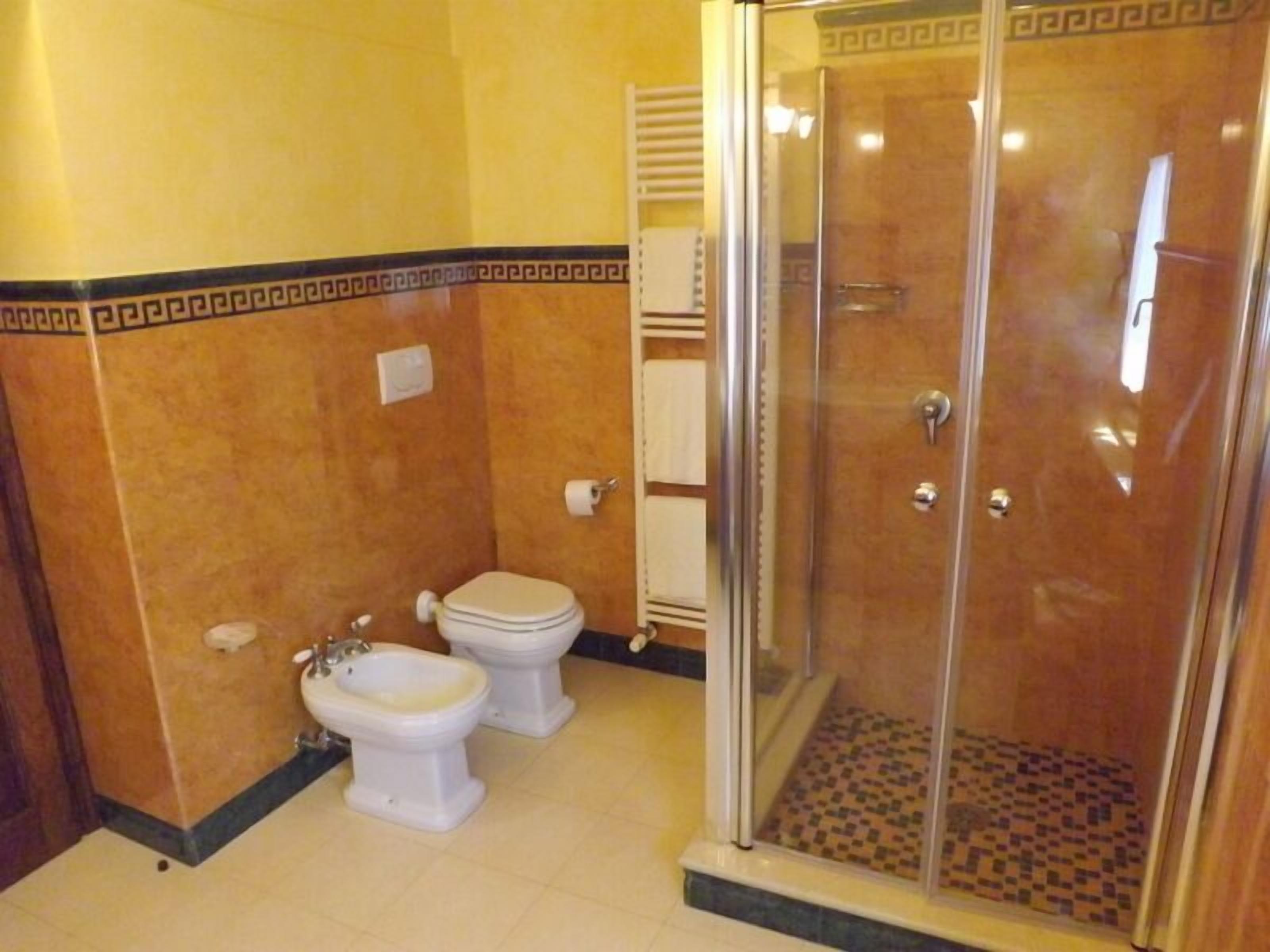 Ein Badezimmer mit zwei Toiletten, einem Bidet und einer Duschkabine.