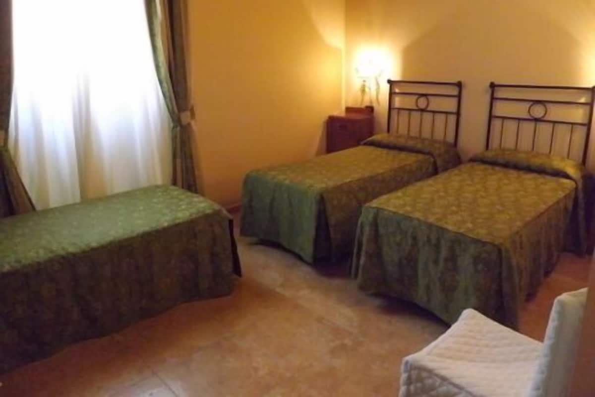 A room with two single beds, a chair, and a nightstand.