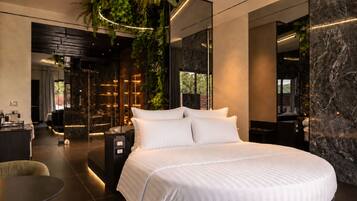 A modern hotel room with a large bed, a seating area, and a view of the outdoors.
