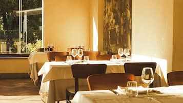 Un restaurante con mesas preparadas para comer, un cuadro grande en la pared y una lámpara de araña.