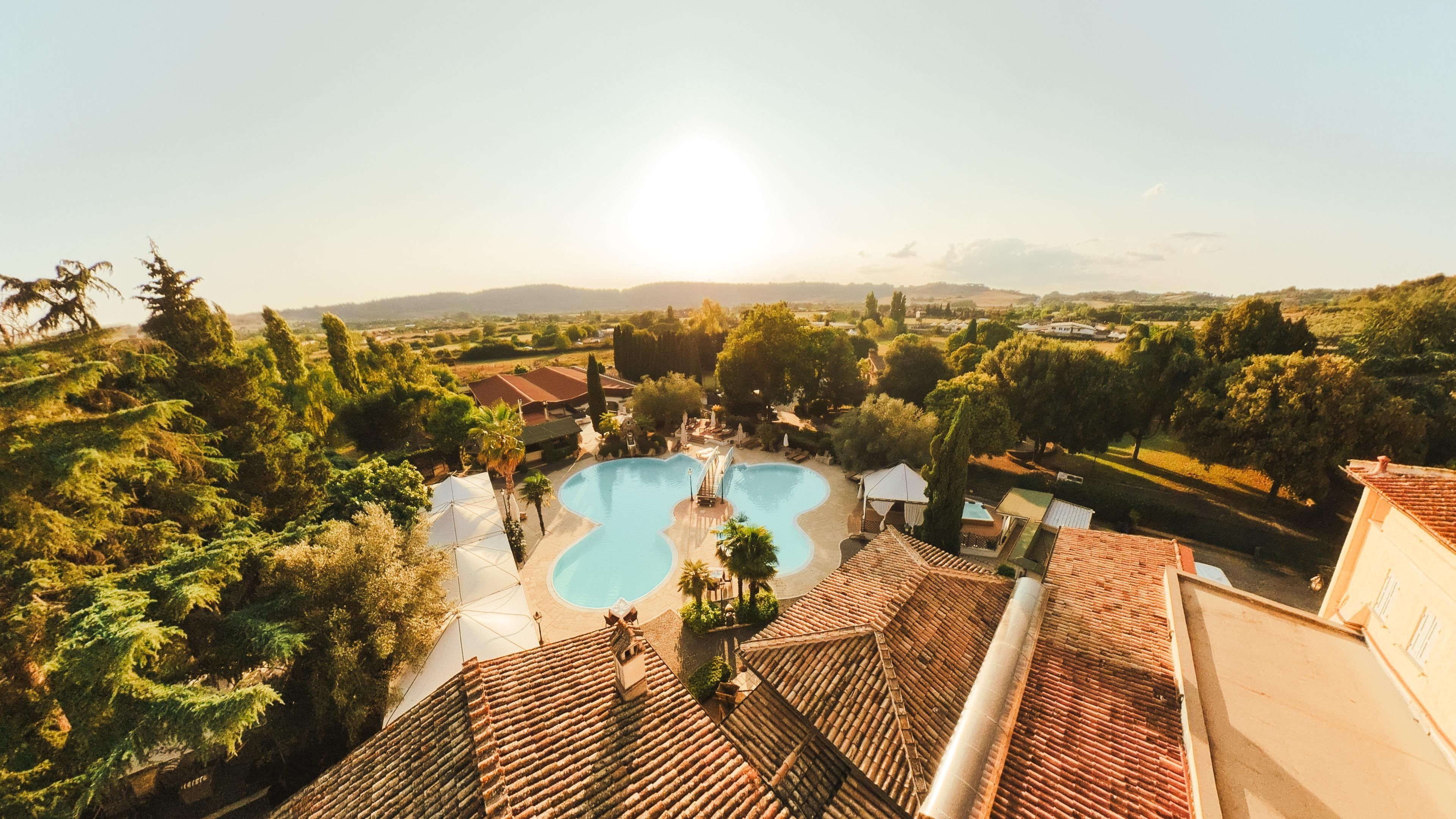 Una piscina rodeada de vegetación exuberante y un techo con tejas.