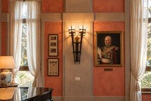 Een kamer met een lijstwerkportret, een wandlamp en een tafel met een lamp.
