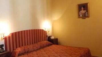 A bedroom with a bed, a nightstand, a lamp, and a wall-mounted picture.