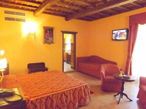 Une chambre d’hôtel avec un lit, un canapé, une petite table, une télévision et une chaise.