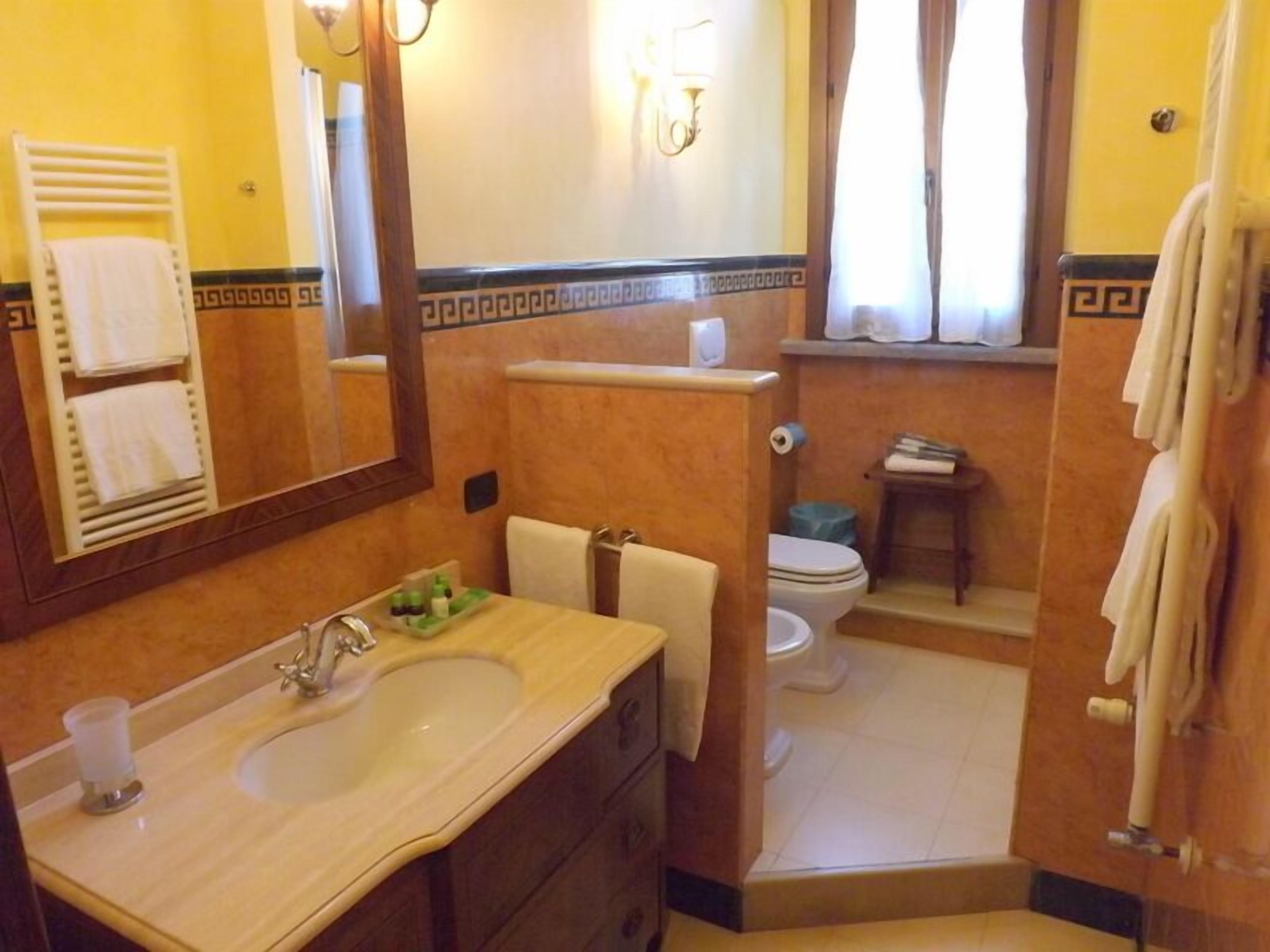 A bathroom with a sink, mirror, towel rack, and toilet.