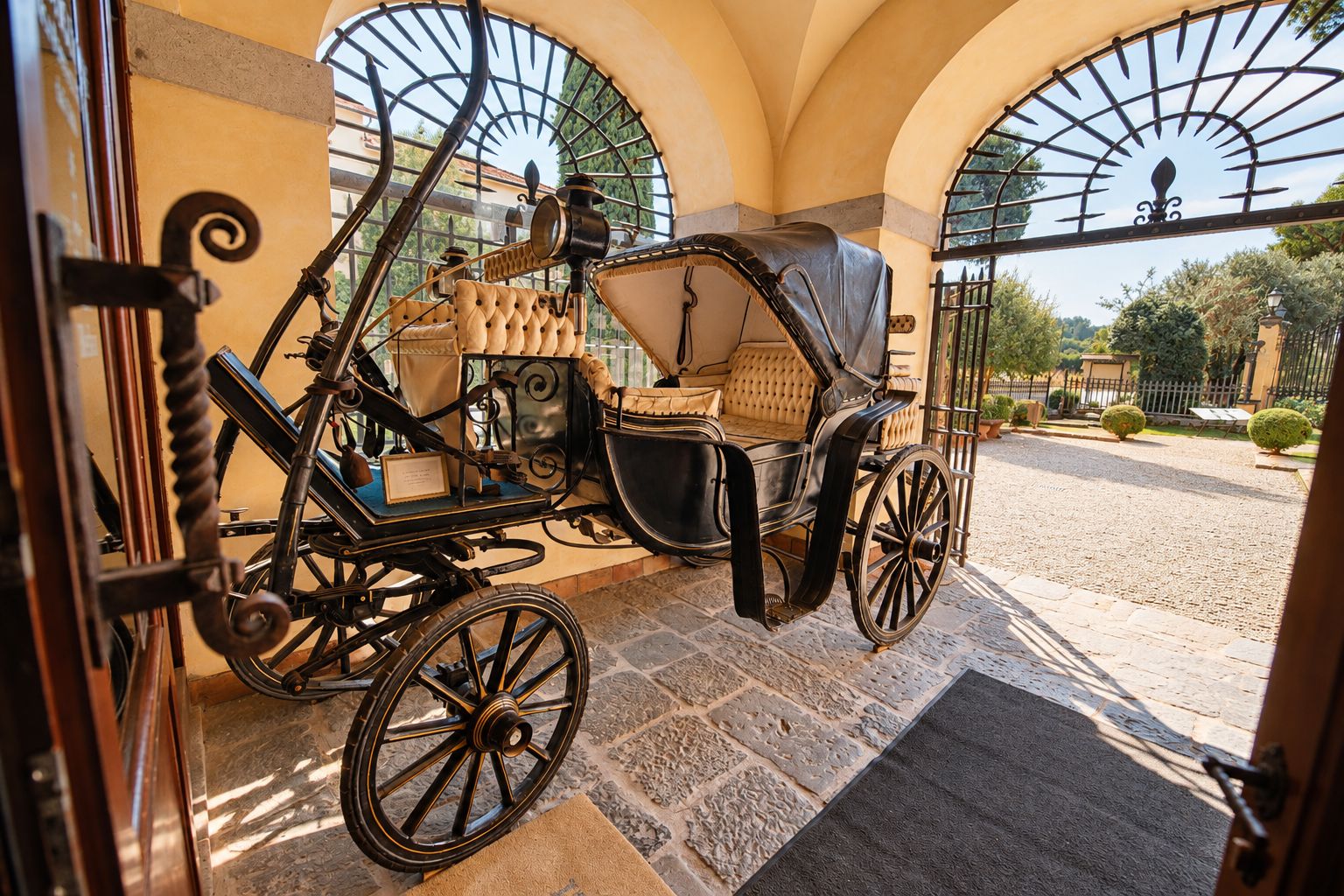 A carriage parked in a covered area with stone flooring and arched windows.