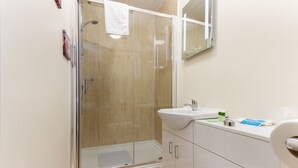 A modern bathroom with a glass-enclosed shower, a white sink, and a toilet. - The Almeria (Blackpool)