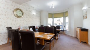 A conference room with a wooden table, black chairs, a clock on the wall, and a window with a view of the street. - The Almeria (Blackpool)