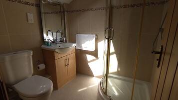Een badkamer met toilet, wastafel en douche.