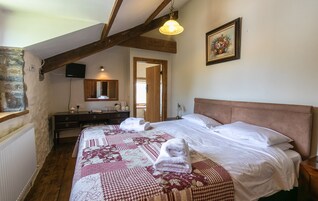Un dormitorio con techo de madera, una cama con colcha floral, una mesita de noche y un espejo.