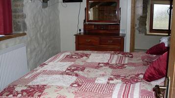 A bedroom with a large bed, a wooden dresser, a mirror, and a window.