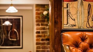 A room with a checkered floor, a leather armchair, a wooden column, and a painting on the wall.