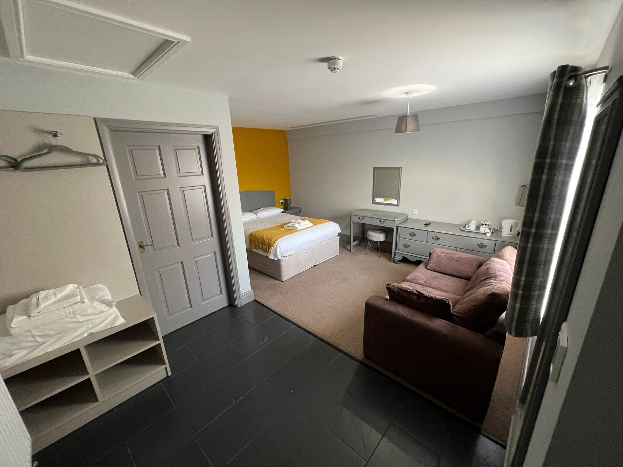 Une chambre à coucher comprenant un lit, une commode, une chaise et une armoire.