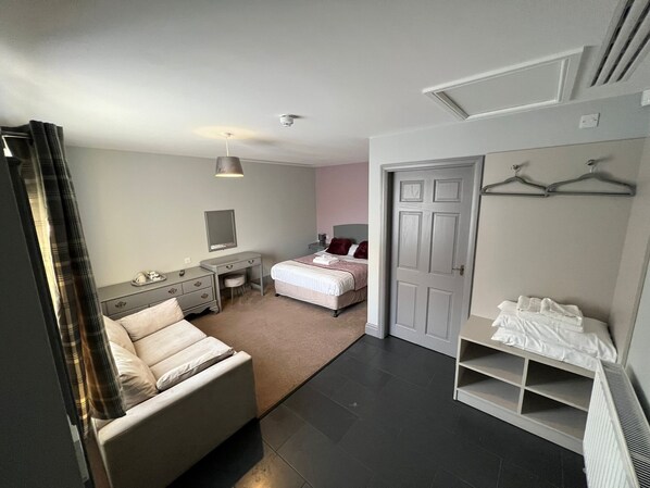 A modern bedroom with a bed, bedside table, dresser, and a walk-in closet with shelves. - The Black Horse Inn (Gainsborough)