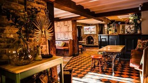 A cozy bar area with a checkered floor, wooden furniture, and a rustic stone wall.