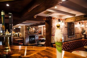 A cozy bar area with wooden flooring, a brick fireplace, and a leather booth. - The Black Horse Inn (Gainsborough)