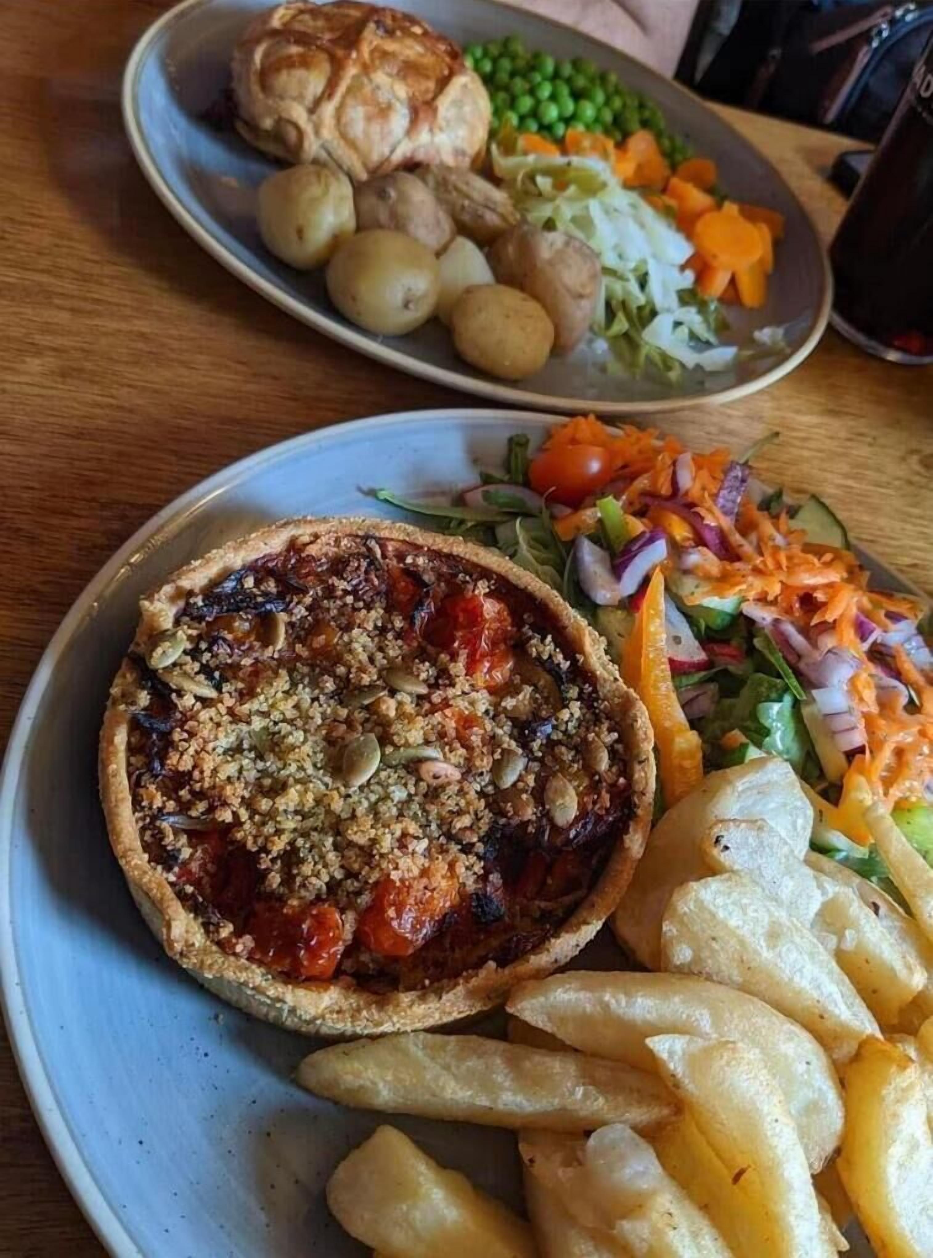 Een bord met een pastei, salade en frieten.