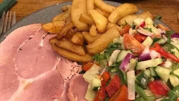 Un plato de comida con jamón, papas fritas, ensalada y un bistec.
