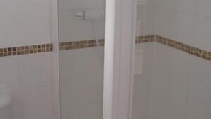 Un baño con azulejos blancos y un borde marrón.