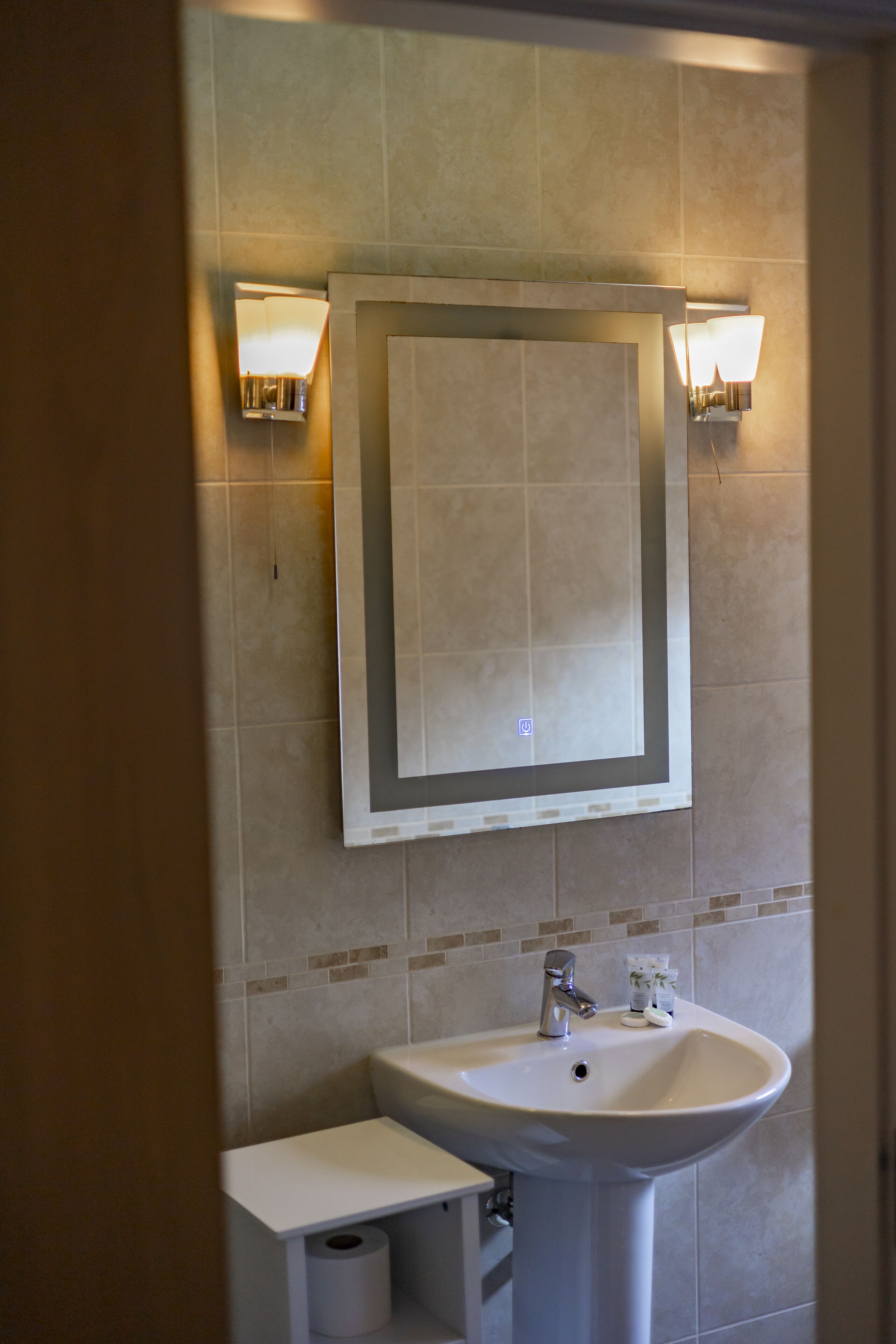 A bathroom with a sink, mirror, and two wall-mounted lights.