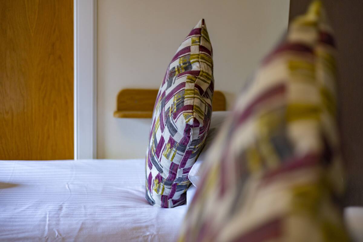 A bed with a patterned pillow and a wooden headboard.