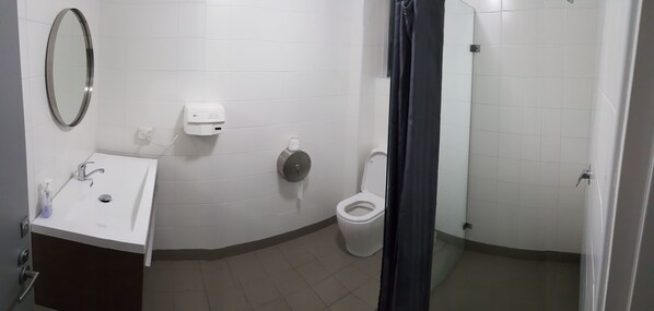 A bathroom with a sink, mirror, toilet, and hand dryer.