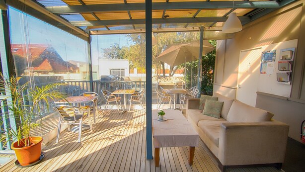 Eine überdachte Terrasse mit einer Couch, einem Tisch und Stühlen.