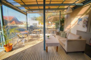 A covered outdoor patio with a sofa, table, and chairs. - Cambridge Lodge - Hostel (Stanmore)