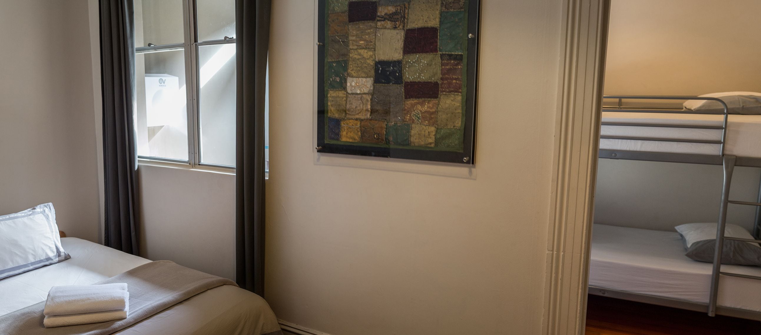 Ein Zimmer mit einem Bett, einem Etagenbett, einem Fenster und einer Steppdecke.