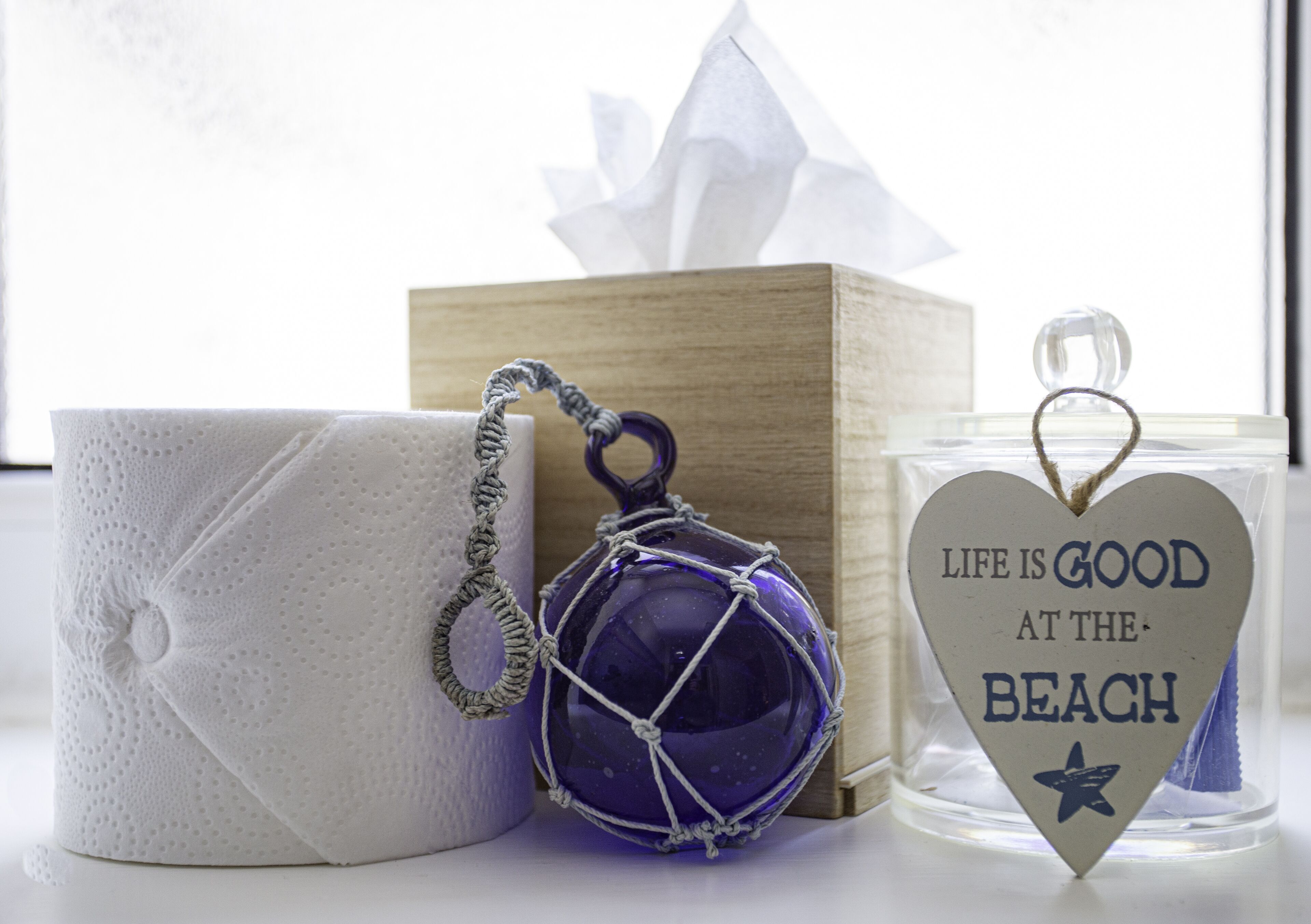 Eine Taschentuchbox, eine dekorative Glasverzierung und ein herzförmiger Kerzenständer mit Strandmotiv.
