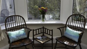 Two wooden chairs with cushions, a small table, and a vase with flowers on a windowsill. - Mariners Guest House (Plymouth)