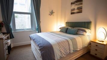 A neatly arranged bedroom with a bed, bedside lamps, a star decoration, and a window with curtains.