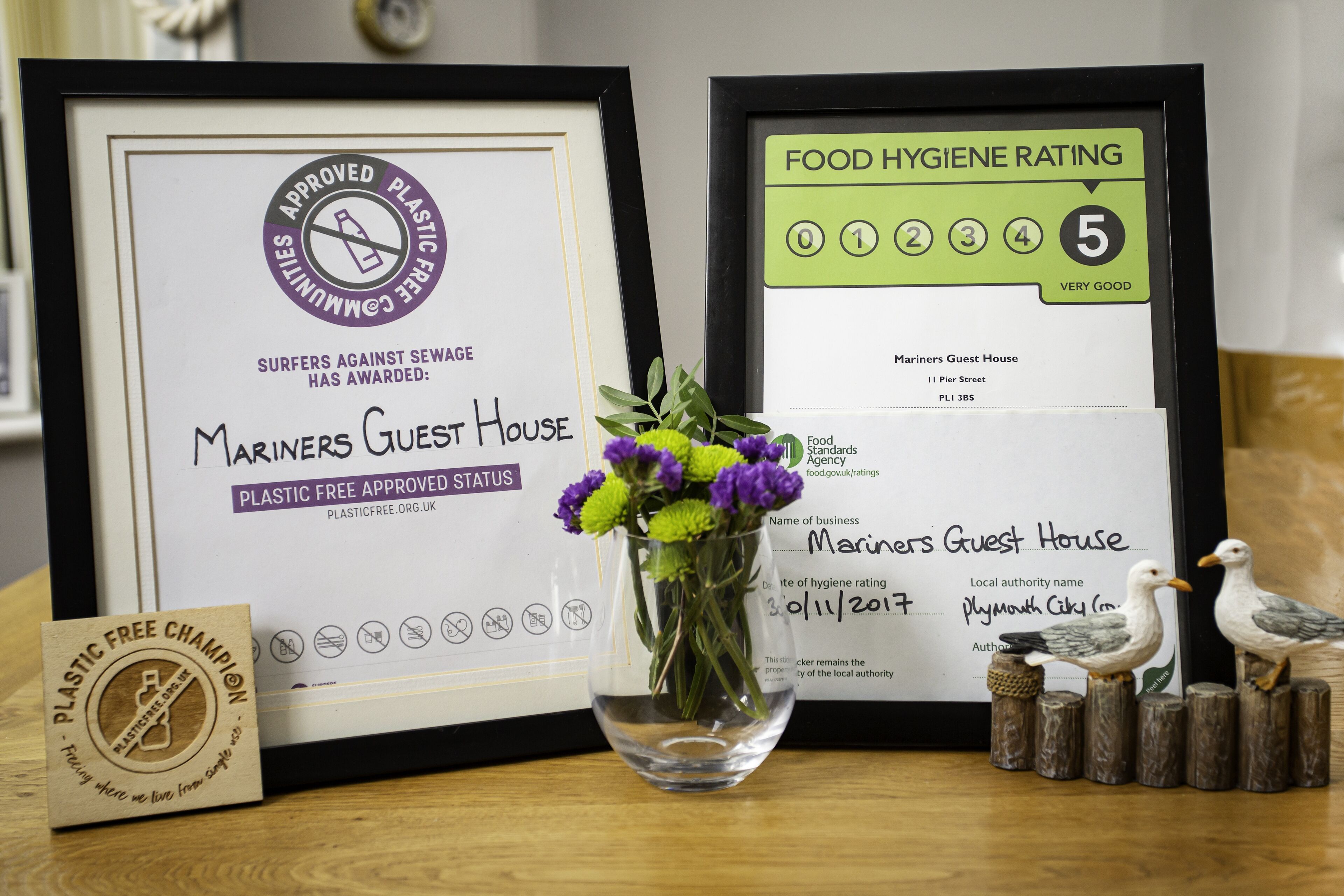 Framed awards and certificates for Mariners Guest House, including a plastic-free status and a food hygiene rating of 5.