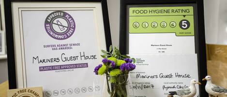 Framed awards and certificates for Mariners Guest House, including a plastic-free status and a food hygiene rating of 5.
