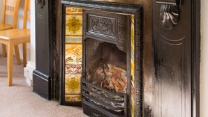 A fireplace with a decorative mantle, a wooden chair, and a painting on the wall. - Mariners Guest House (Plymouth)
