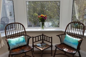 Two wooden chairs with cushions, a small table, and a vase with flowers on a windowsill. - Mariners Guest House (Plymouth)