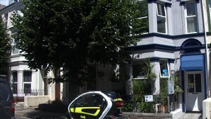 A vehicle parked on a street with a tree and buildings in the background. - Mariners Guest House (Plymouth)