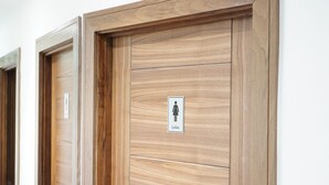 Eine Holztür mit einem Schild, das auf eine Damentoilette hinweist.