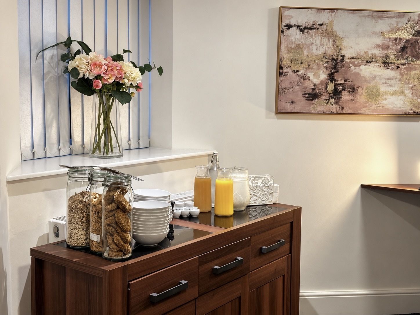 A breakfast bar with a vase of flowers, a painting, and various breakfast items.