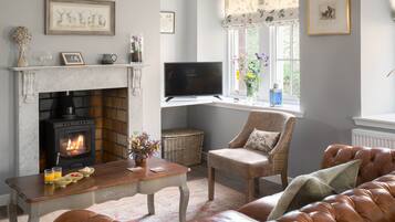 A cozy living room with a fireplace, comfortable seating, and artwork on the walls.